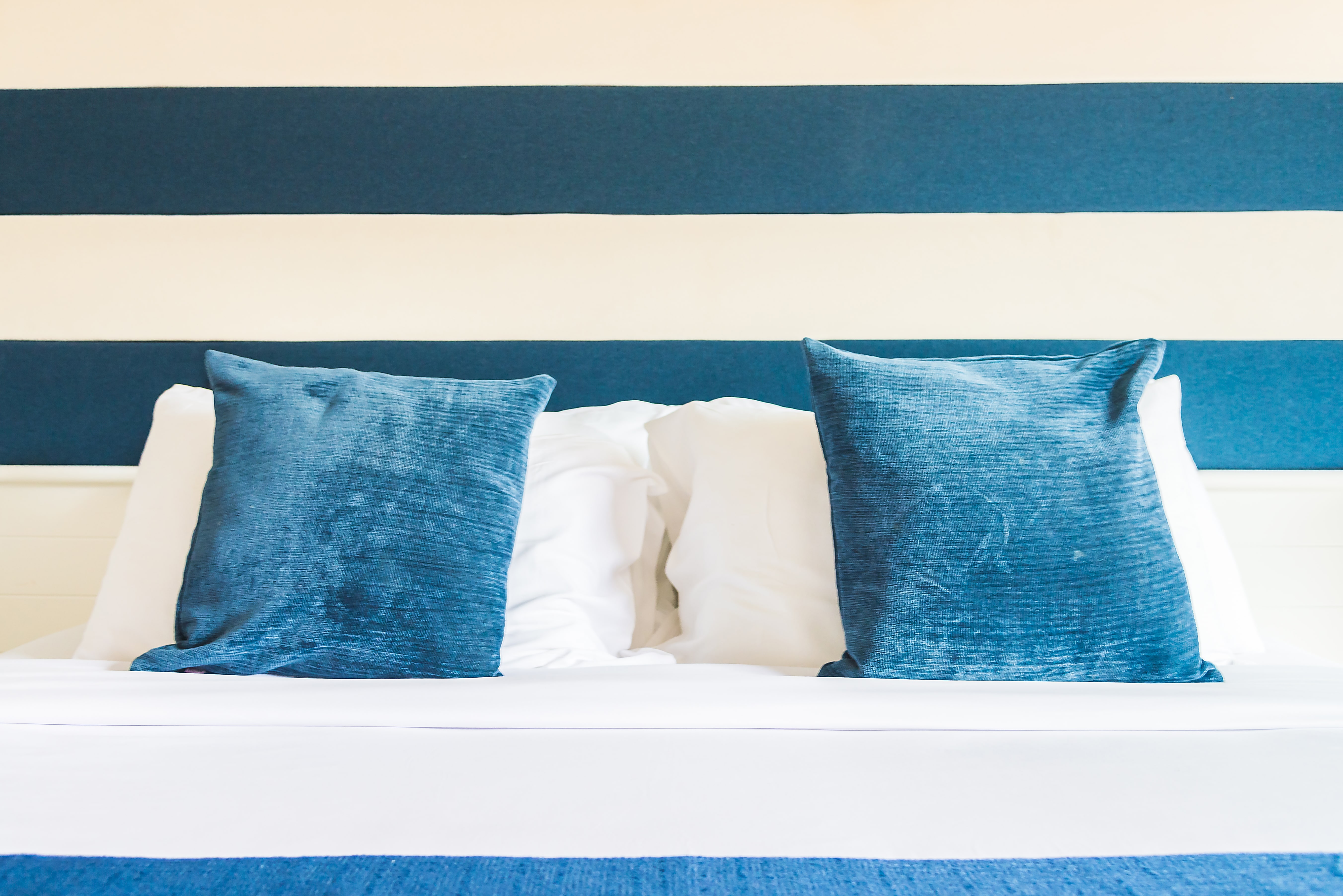 A beautifully arranged bed with vibrant green and pink pillows, alongside a vase of tall grass, enhancing the room's decor.